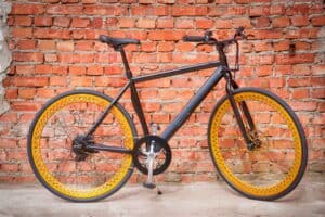 Black eBike with Orange Wheels Against Brick Wall