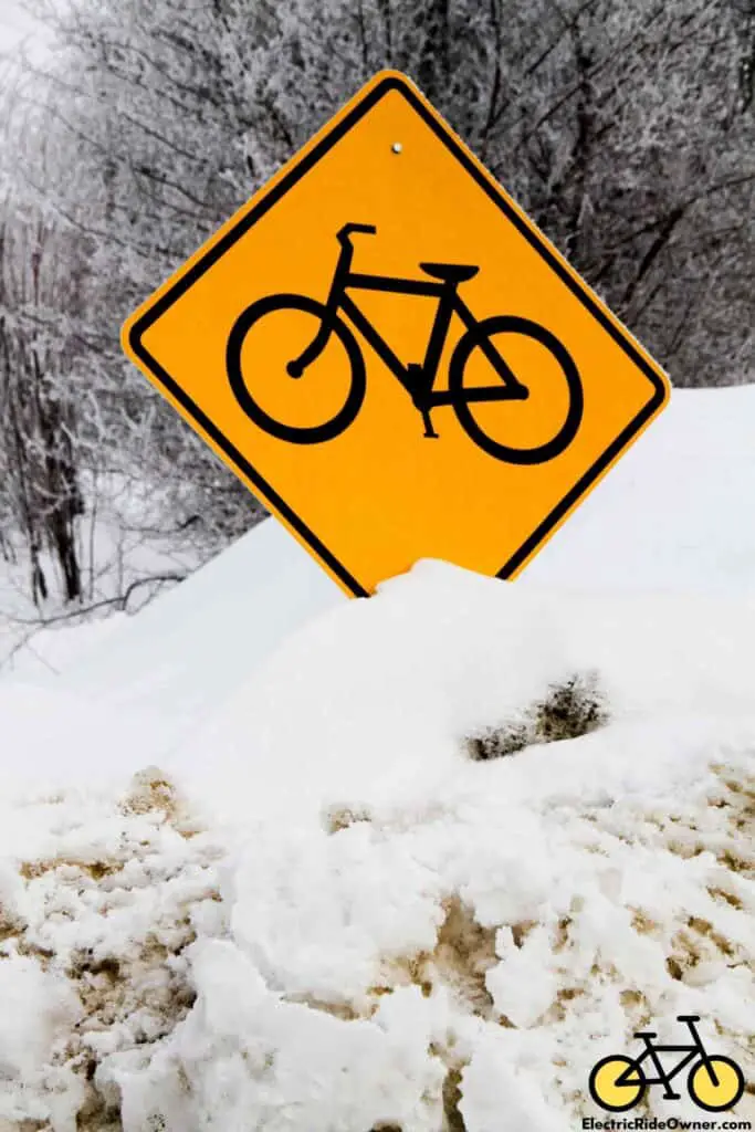 Orange Road Sign with Image of Black Bike Nearly Buried in Snow