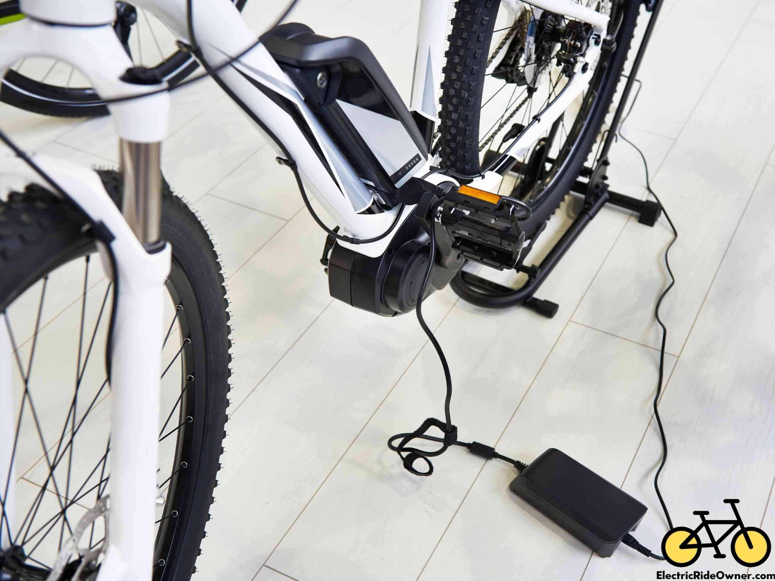 electric bike white frame charging battery on floor