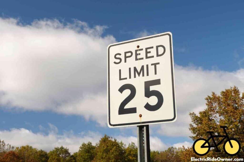 speed limit 25mph sign against blue sky with clouds and treetops background