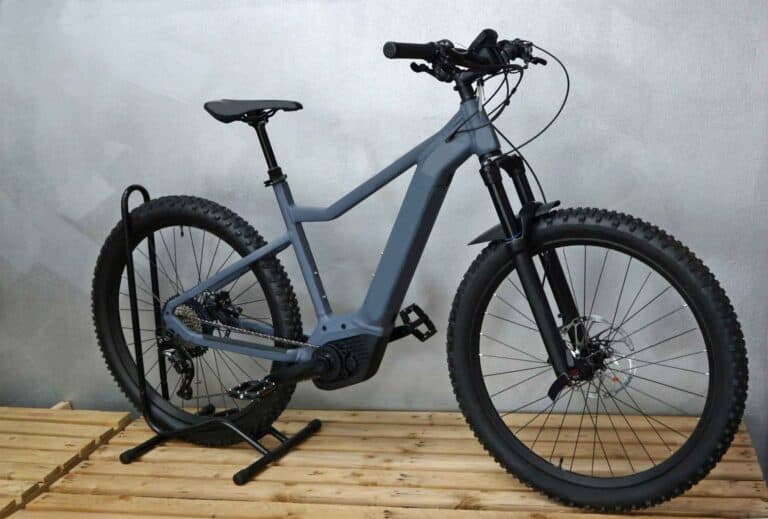 electric bike with grey frame on wood floor against grey wall