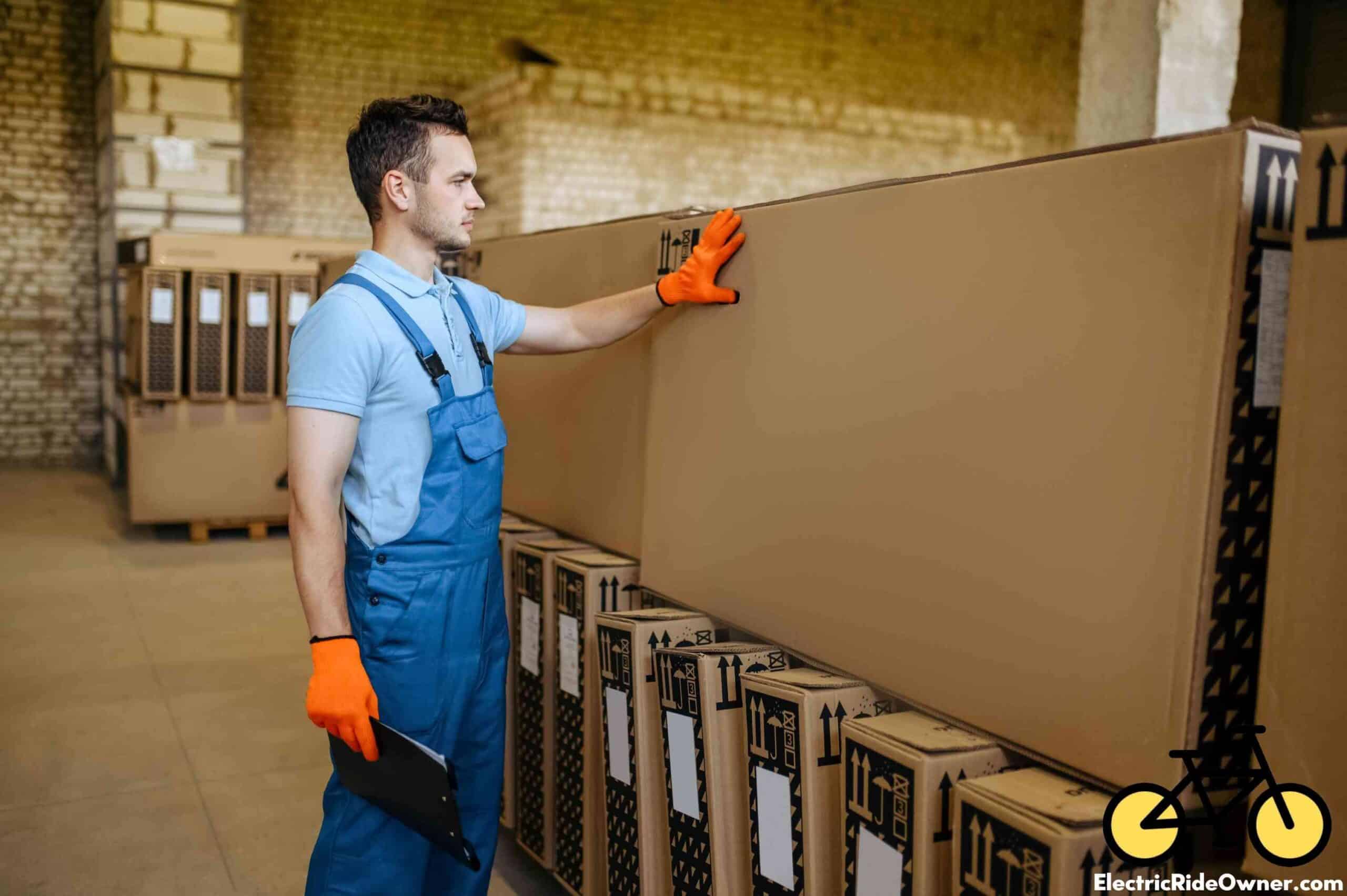 Factory worker steadies large box perpendicularly on top of other large boxes