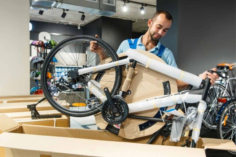 Person lowers ebike with foam padding around frame into a cardboard box