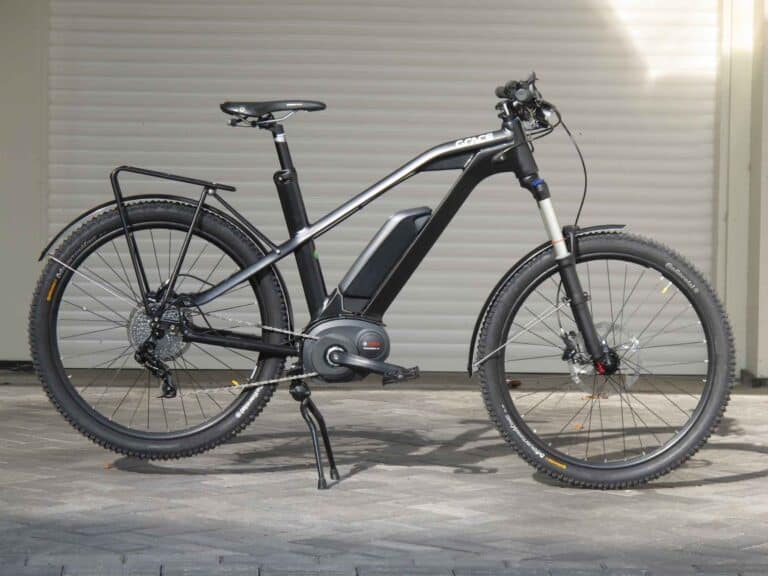 ebike with black and silver frame on pavement with garage door in background