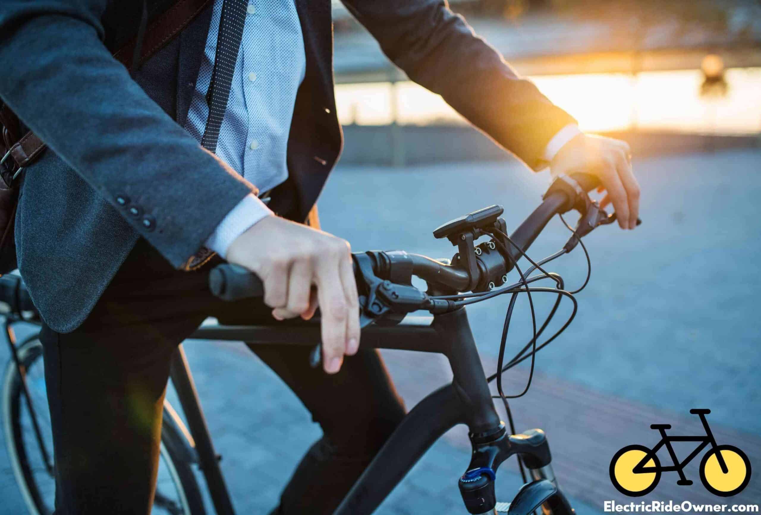 midsection of a man in a suit on an ebike with both hands on each throttle of the ebike with sun setting in background