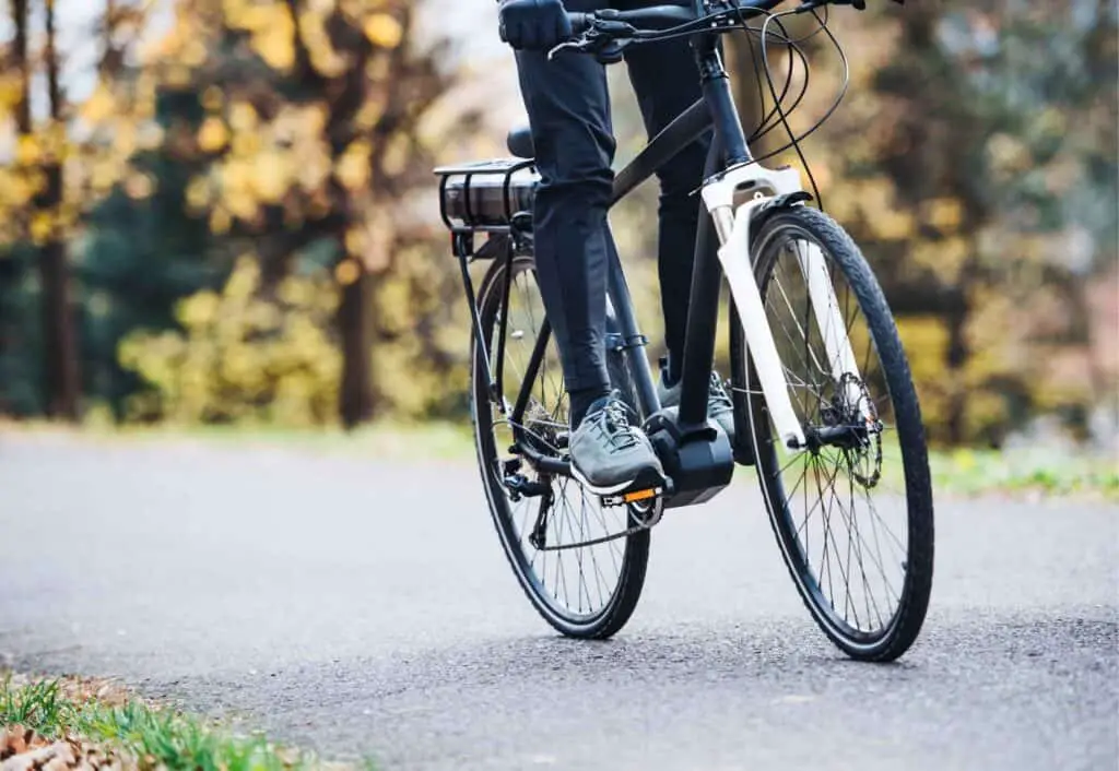 person riding ebike outside on pavement standing on ebike with mid-drive motor